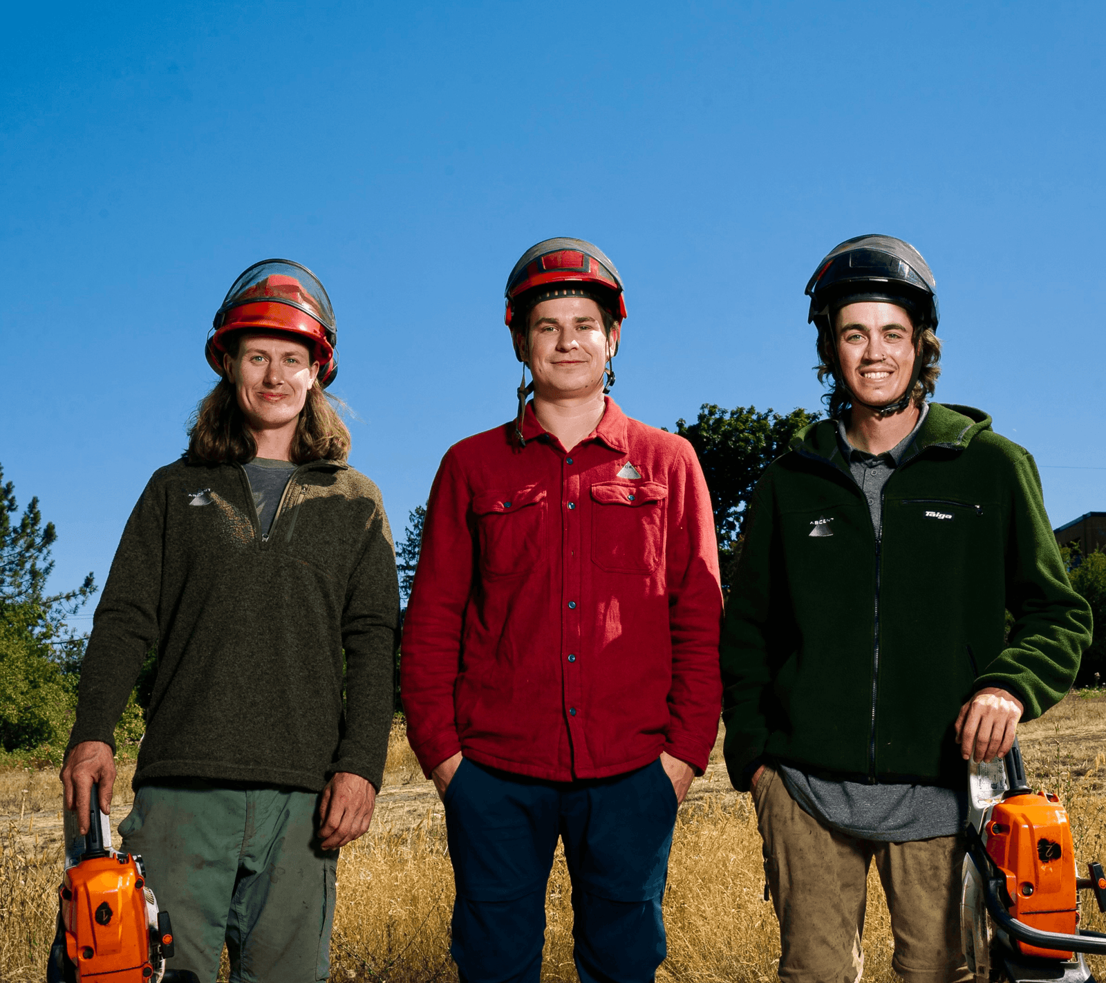 Three Ascent Yard Care crew members standing in a golden field with their equipment